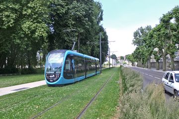 Blaue Straßenbahn in Besançon fährt auf Rasengleis, daneben die versiegelten Fahrspuren für den Autoverkehr. 