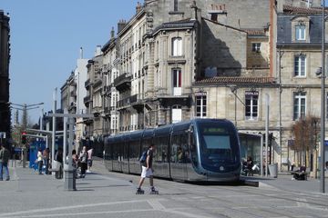 Straßenbahn in Bordeaux von Häuserzeile mit Inlineskater