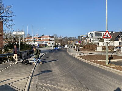 Drei Personen, queren zu Fuß den Alten Steinberger Weg in Höhe Schlesische Straße. 